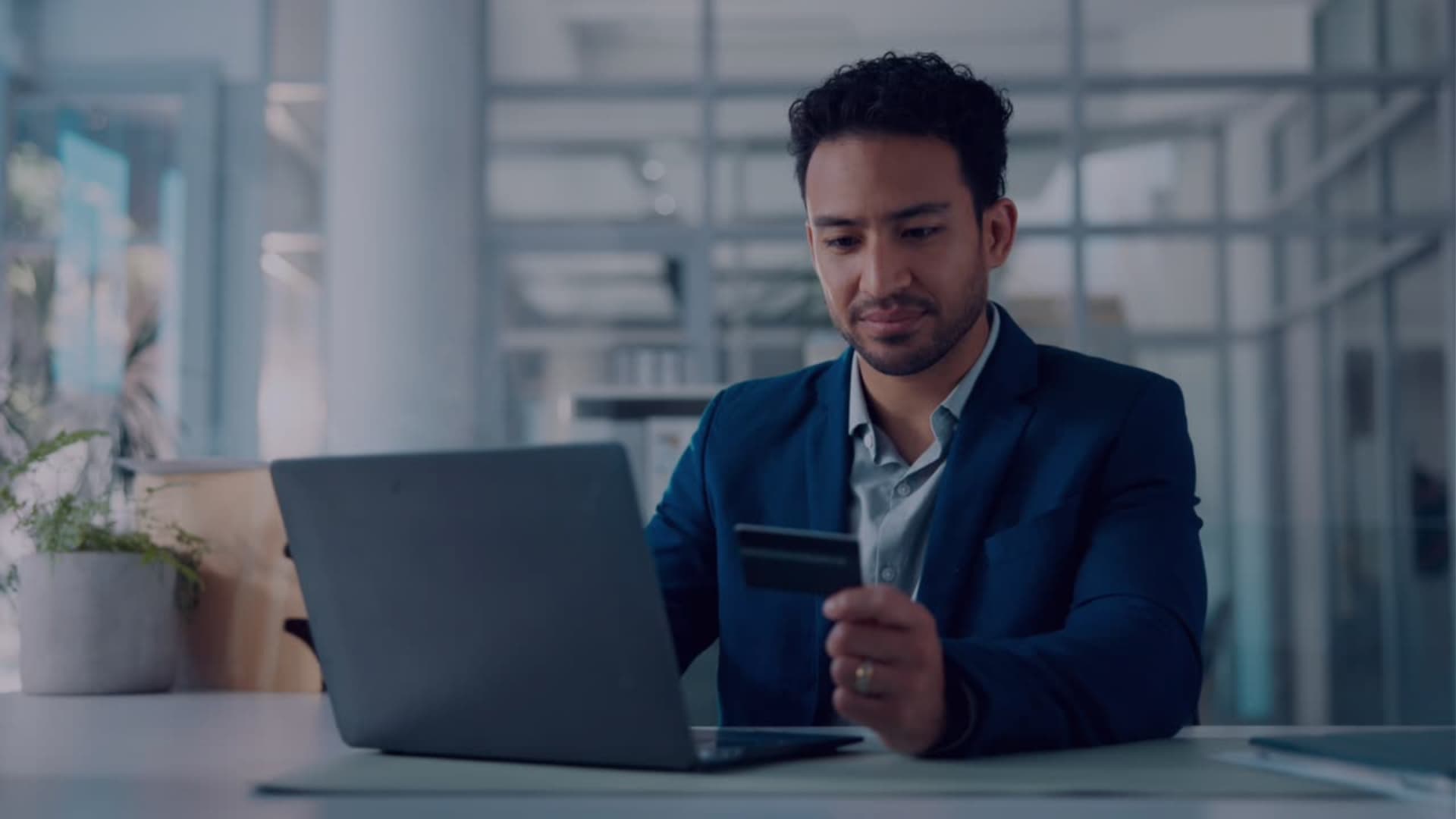 Professional using a laptop and card in an office